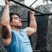 Muscular man in blue tank top performing pull-ups outdoors in Mexico City.